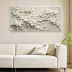 Decorative wall art with floral design above a white sofa in a living room.