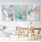 Three abstract art pieces on a wall above a dining table with chairs.
