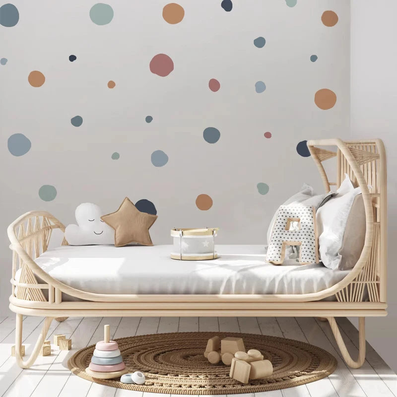 Children's room with a wicker crib, colorful polka dot wall, and toys on a wooden floor.