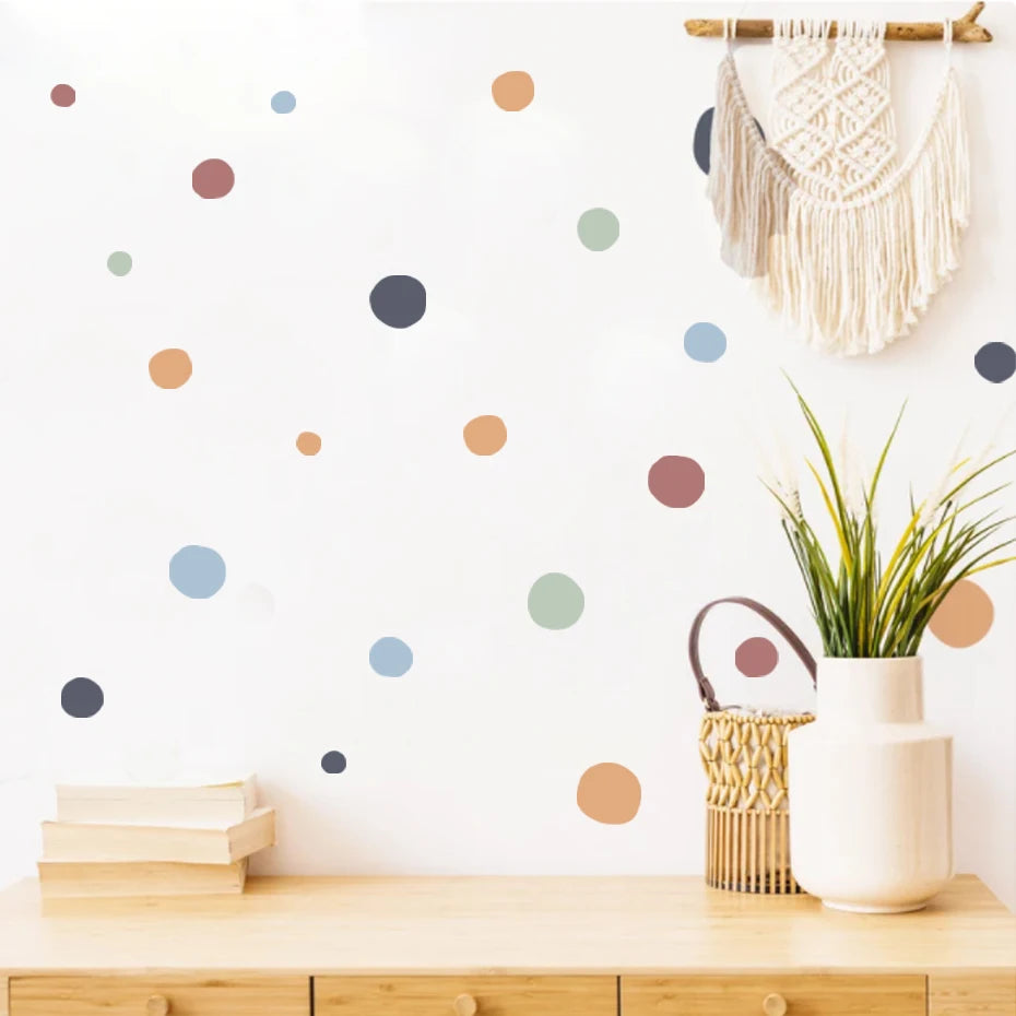 Wall with colorful polka dot decals, wooden shelf, plant, and macrame hanging.