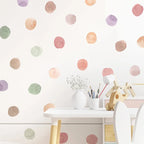 Children's play area with a white table and chairs against a wall with colorful polka dot decals.