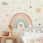 Children's room with a rainbow wall decal, clouds, and hearts on a light-colored wall.