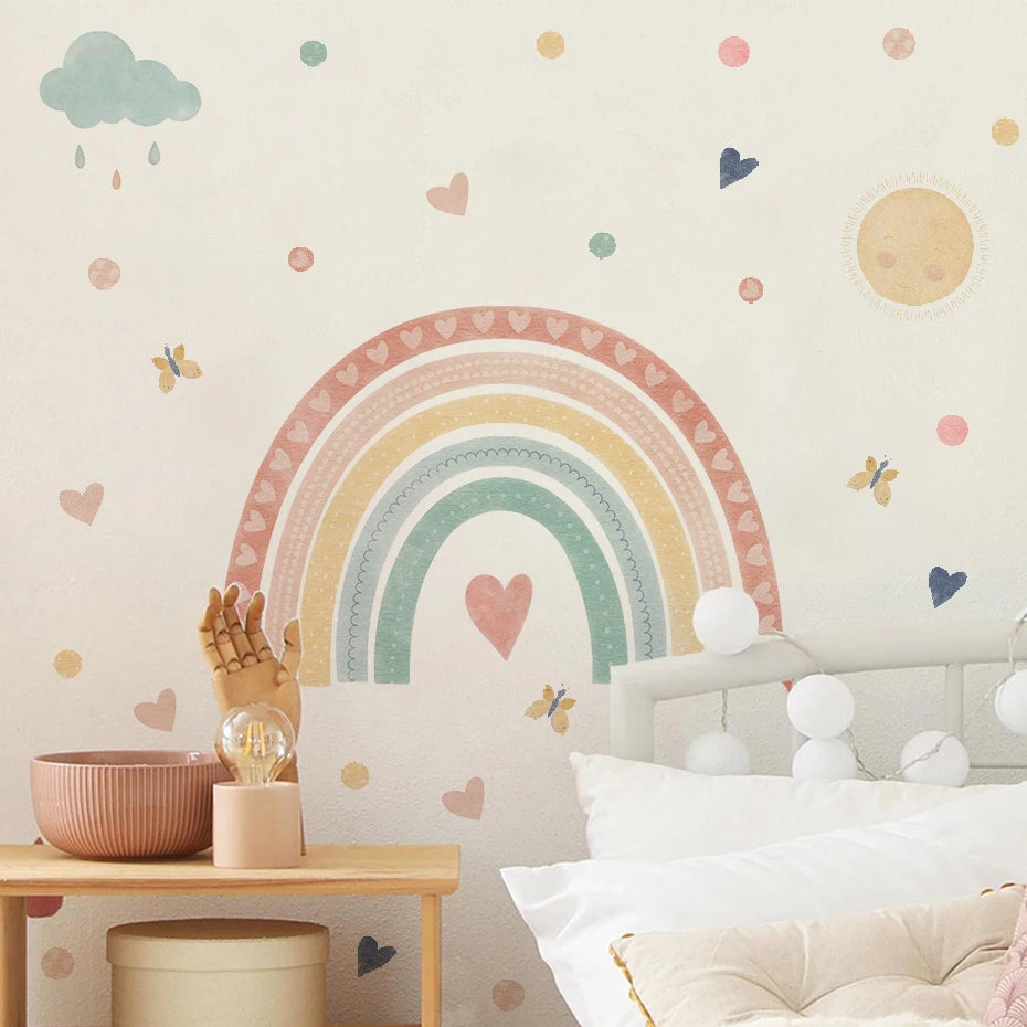 Children's room with a rainbow wall decal, clouds, and hearts on a light-colored wall.