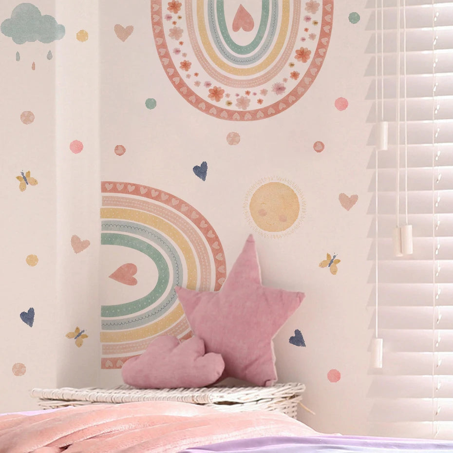 Children's room with pastel-colored wall design featuring rainbows, hearts, and stars, with a pink star-shaped pillow on a bed.