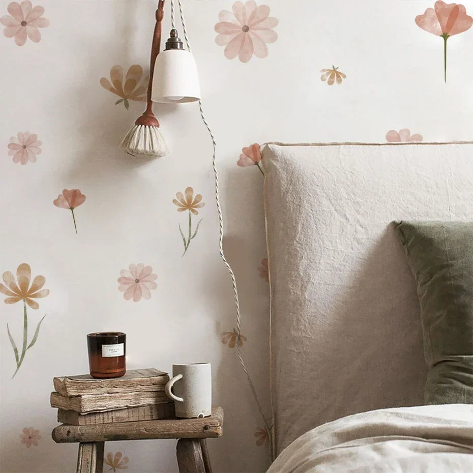 Cozy bedroom with floral wallpaper, a small table with a candle and mug, and a bed with pillows.