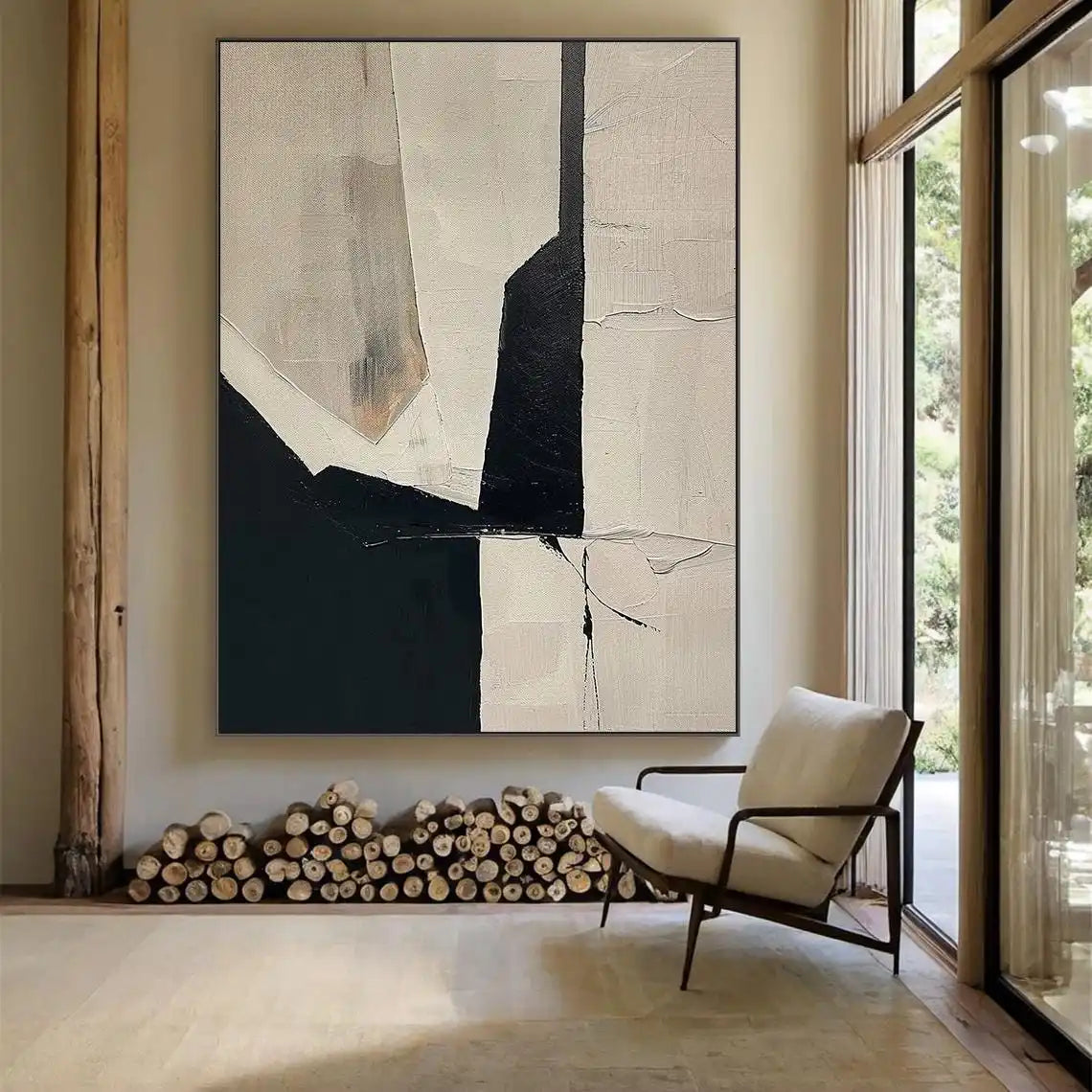 Abstract art piece on a wall above a chair and stacked logs in a room with large windows.
