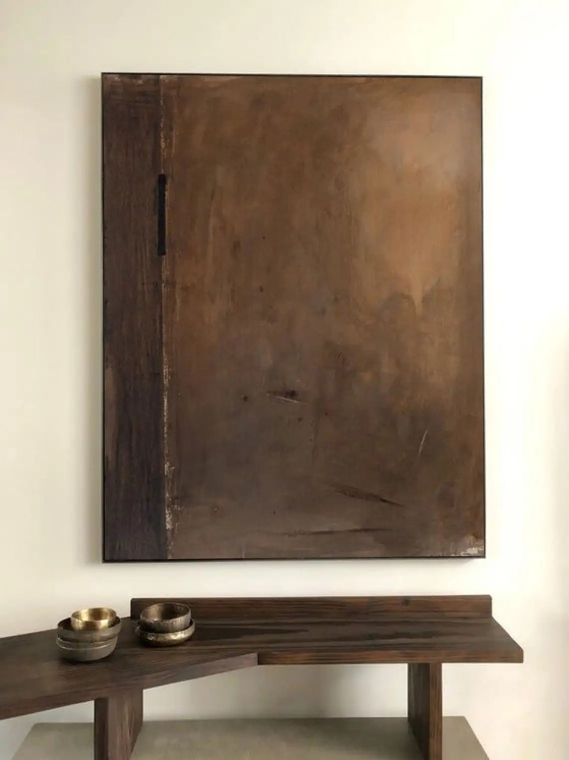 Large abstract painting on a wall above a wooden console table with decorative bowls.