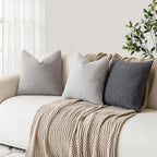 Beige sofa with textured throw blanket and pillows in a bright room.