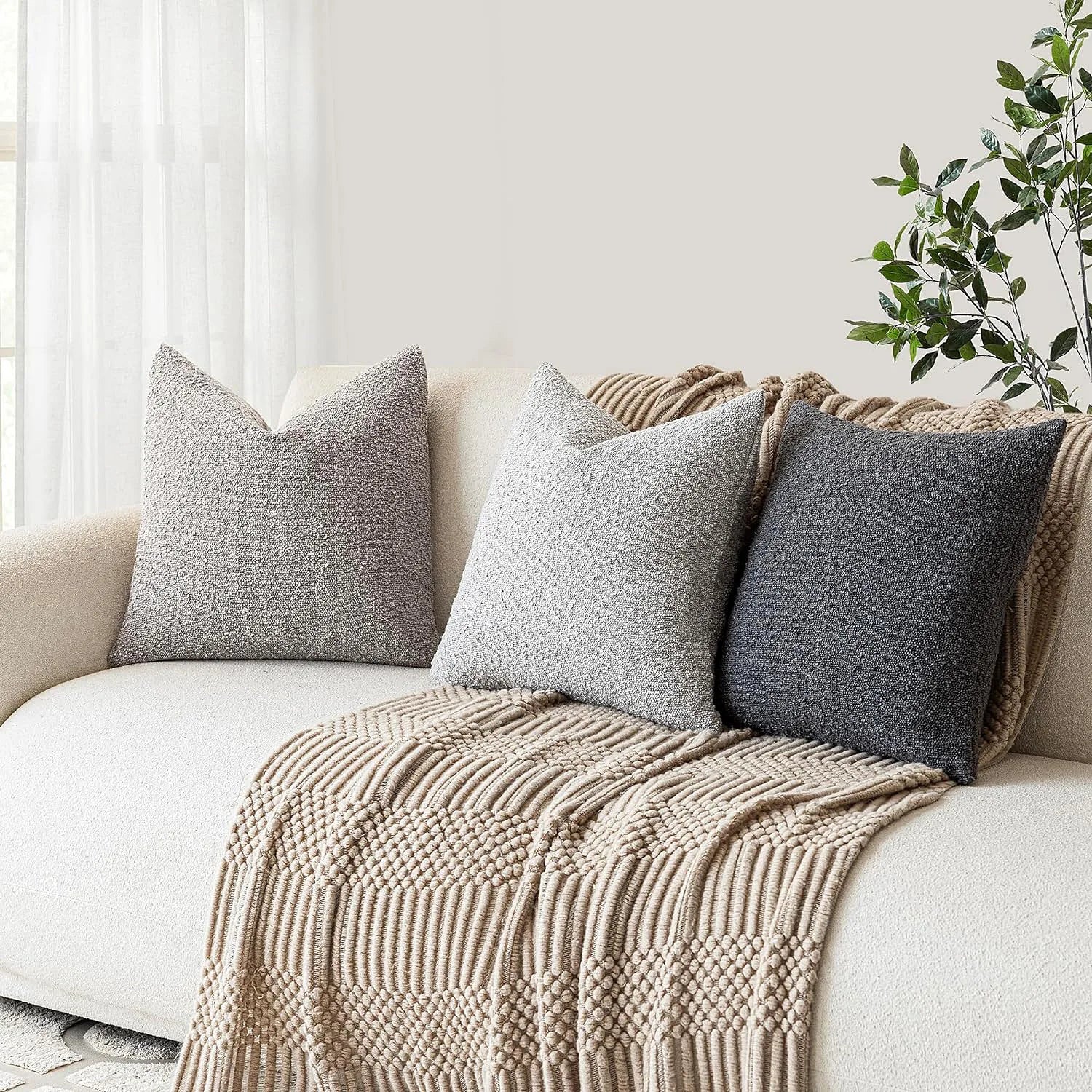 Beige sofa with textured throw blanket and pillows in a bright room.