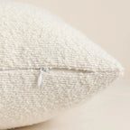 Textured beige pillow with a zipper on a light background