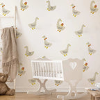 Nursery room with white crib, rocking chair, and teddy bear against a wall with duck pattern.