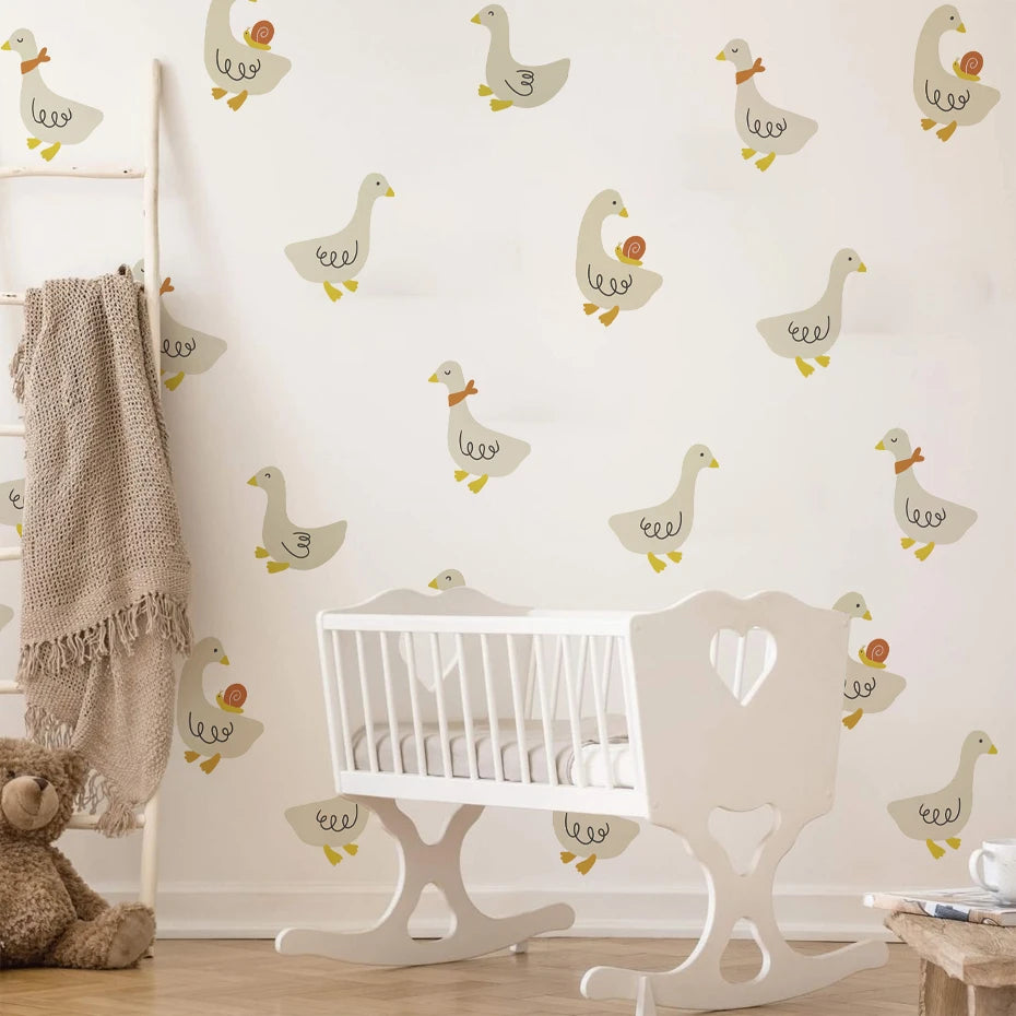 Nursery room with white crib, rocking chair, and teddy bear against a wall with duck pattern.