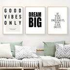 Three motivational posters on a wall above a sofa with cushions.