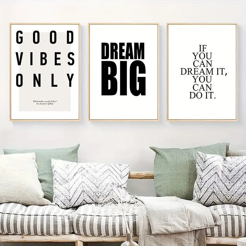 Three motivational posters on a wall above a sofa with cushions.