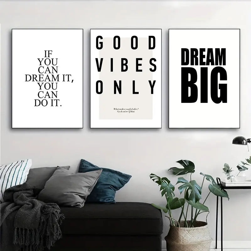 Three motivational posters on a wall above a sofa with decorative pillows and plants.