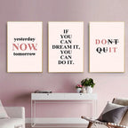 Three motivational posters on a wall with a white console table and chair below.