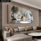 A large rectangular wall art print hangs above a beige sectional sofa in a modern living room. The artwork depicts a sunlit arched corridor with potted trees and a coastal sea view.