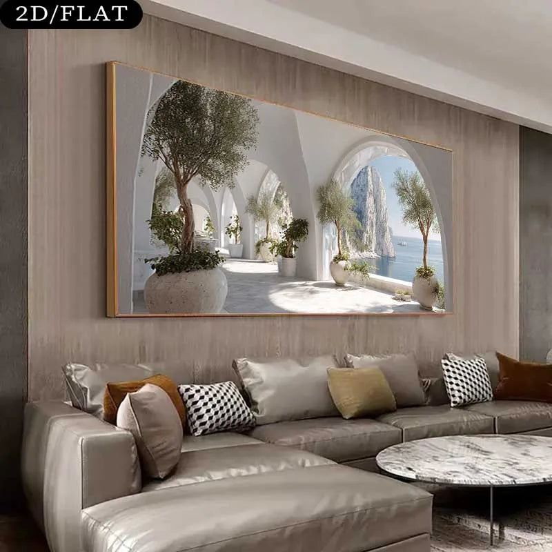A large rectangular wall art print hangs above a beige sectional sofa in a modern living room. The artwork depicts a sunlit arched corridor with potted trees and a coastal sea view.