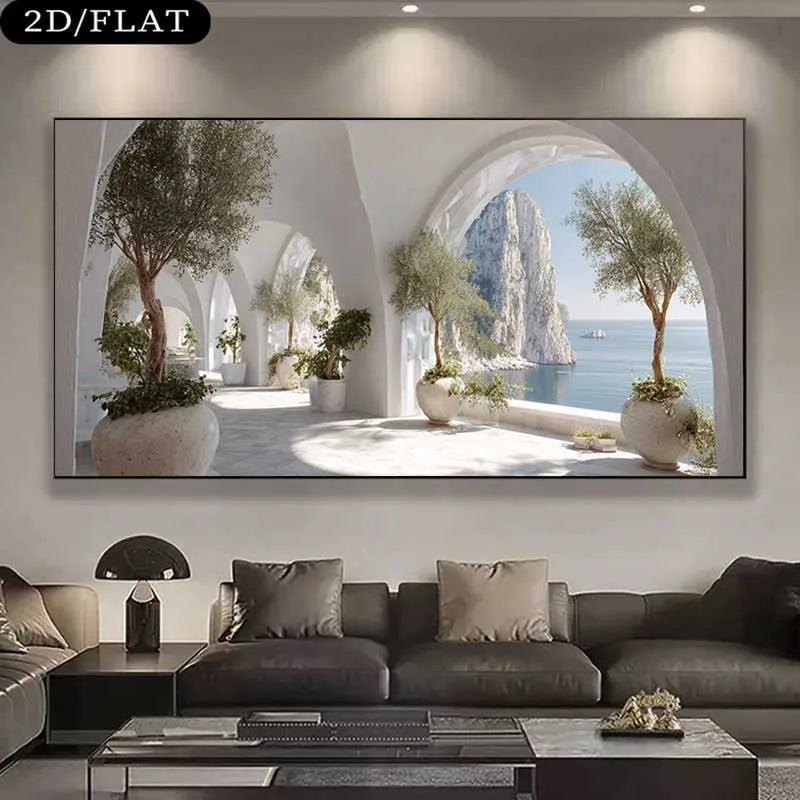 A large wall art print showing a bright Mediterranean-style arched terrace with potted trees and a sea cliff view, displayed above a dark sofa in a modern living room. 