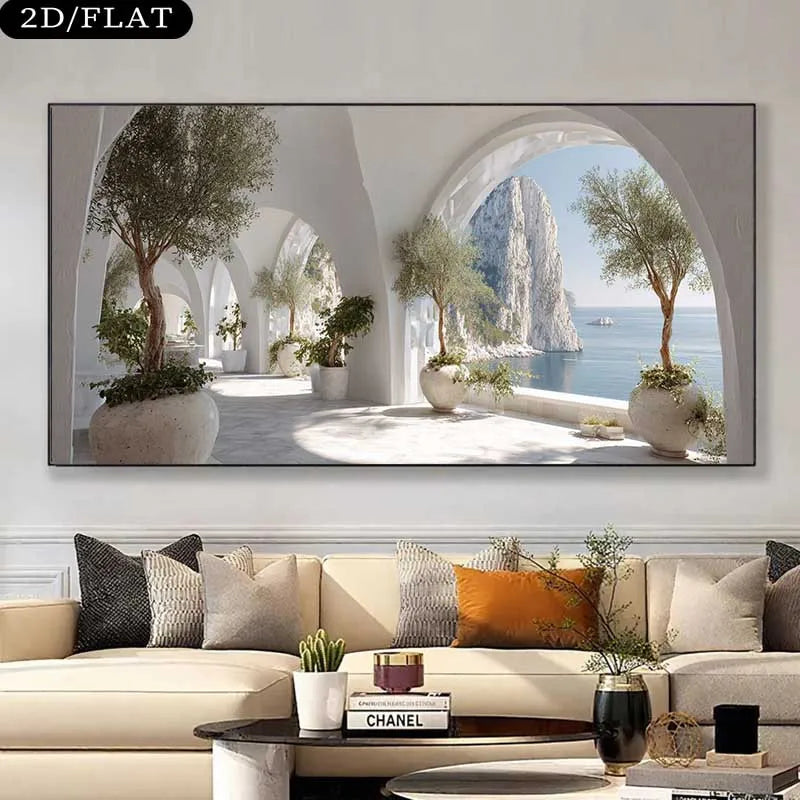 A framed wall art print showing a bright coastal archway scene with potted trees and a blue sea, displayed above a beige sofa in a modern living room. 