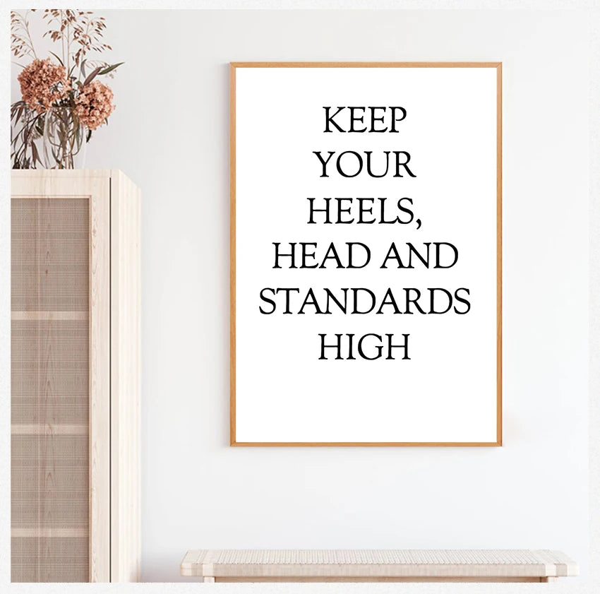 Framed motivational quote 'Keep your heels, head and standards high' on a white wall.
