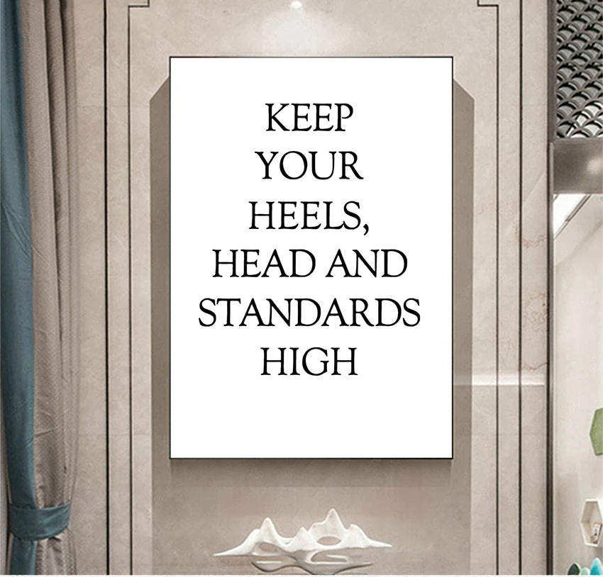 Framed poster with motivational quote 'Keep your heels, head and standards high' on a wall.