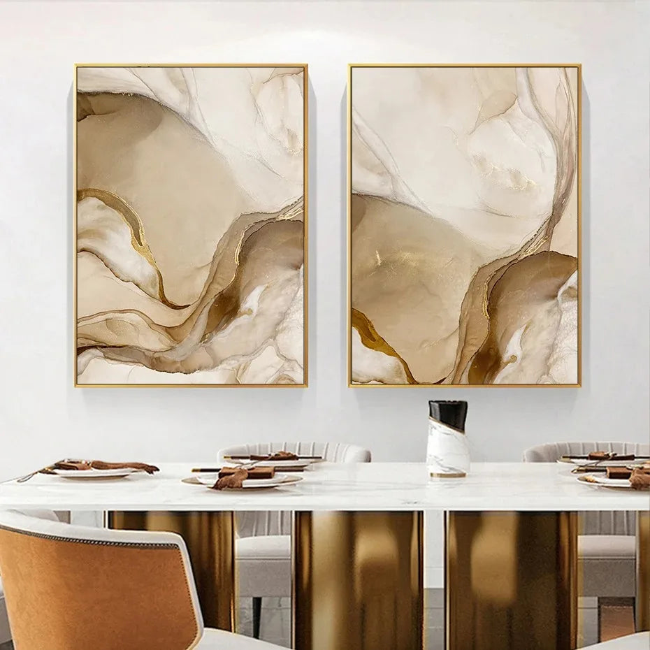 Two abstract art pieces in gold frames on a wall above a dining table.