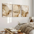 Three abstract wall art pieces in a neutral-toned room with a bed and coffee table.