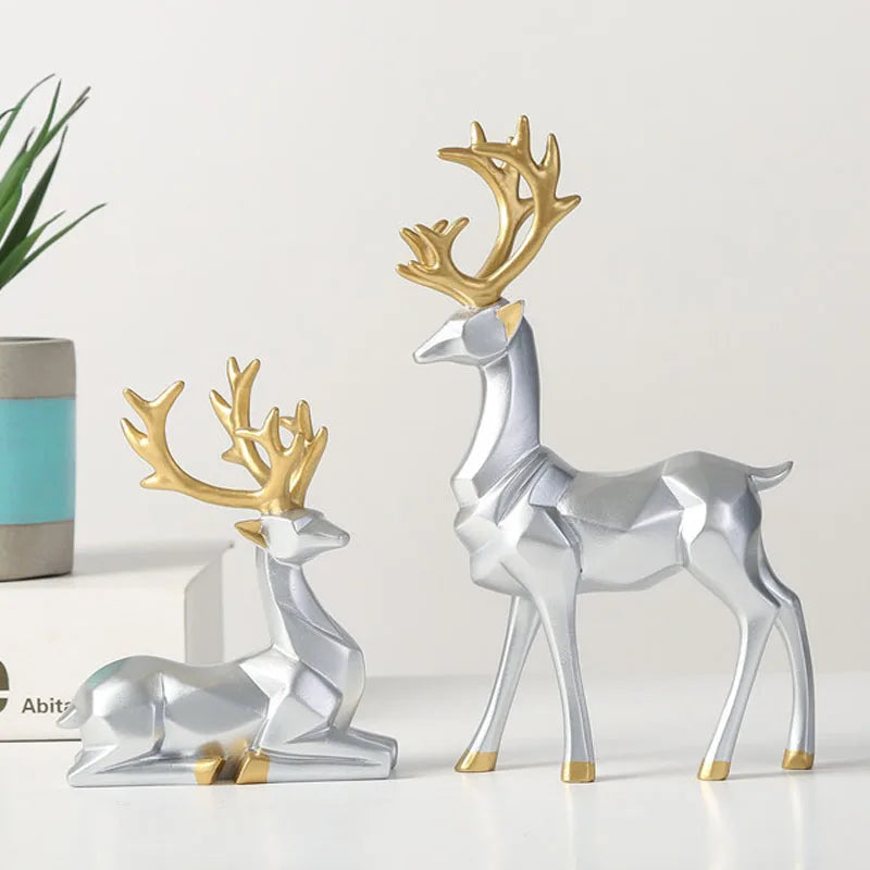 Decorative deer figurines with gold antlers on a white surface.