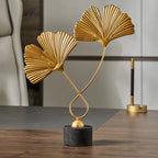 Gold leaf sculpture on a black base in an indoor setting