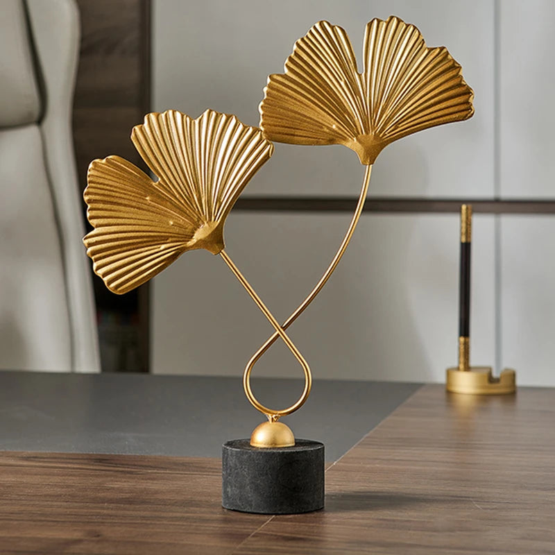 Gold leaf sculpture on a black base in an indoor setting