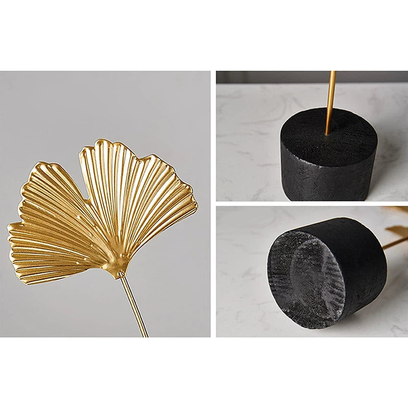 Gold leaf incense holder with black cylindrical bases on a gray background