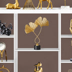 Decorative gold leaf sculpture on a white shelf against a brown wall