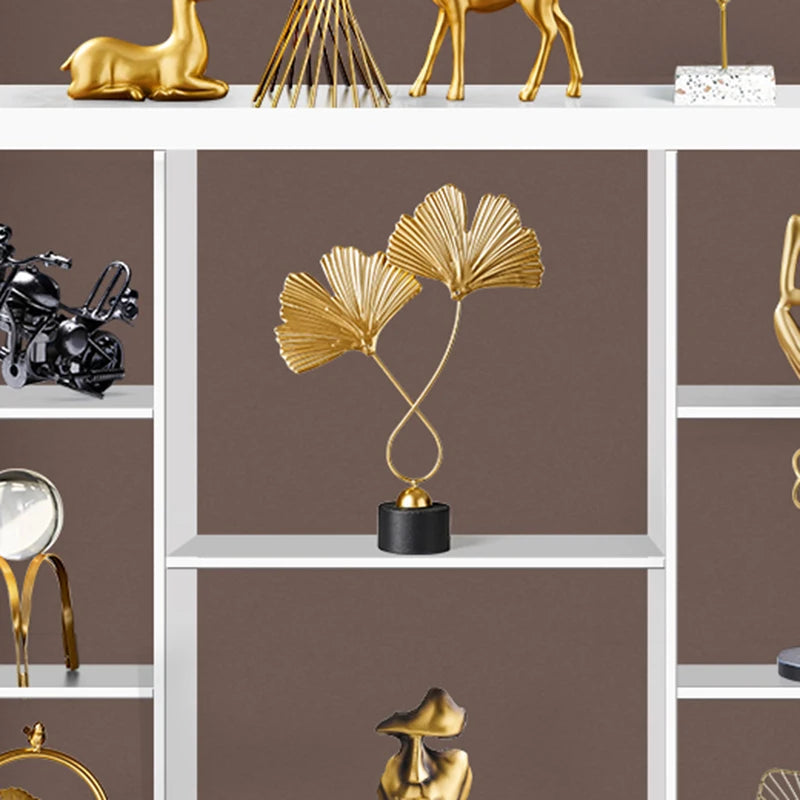 Decorative gold leaf sculpture on a white shelf against a brown wall