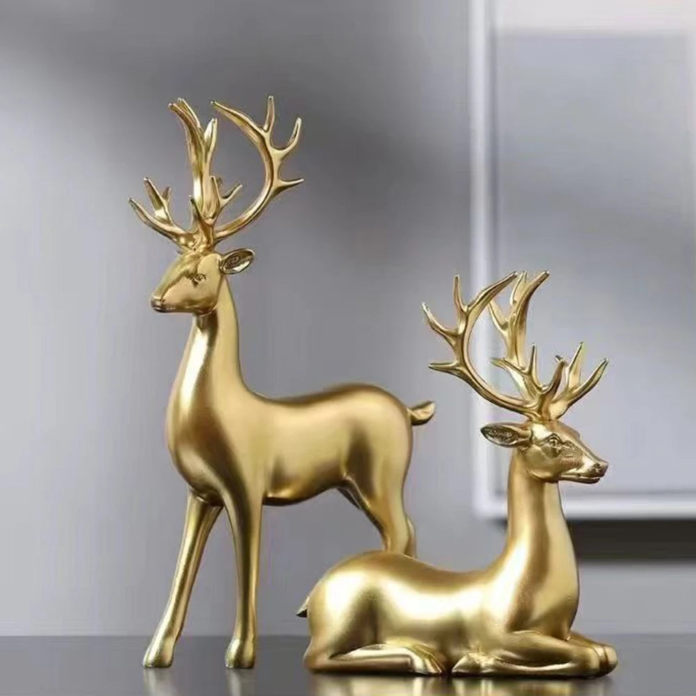 Two gold deer figurines on a reflective surface with a neutral background