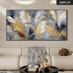 A large rectangular wall art piece showing abstract gold, white, gray, and black feather-like brushstrokes, displayed above a cream sofa in a styled living room. 