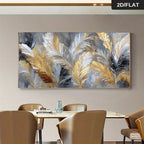 A large rectangular wall art print featuring abstract pampas grass feathers in gold, white, gray, and black, displayed above a dining table with chairs in a modern interior setting.