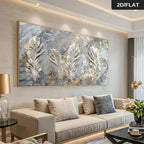 A large rectangular wall art piece featuring three large white feathers with gold and gray marbled textures, displayed above a beige sofa in a modern living room. A black label in the top right corner reads '2D/FLAT'.