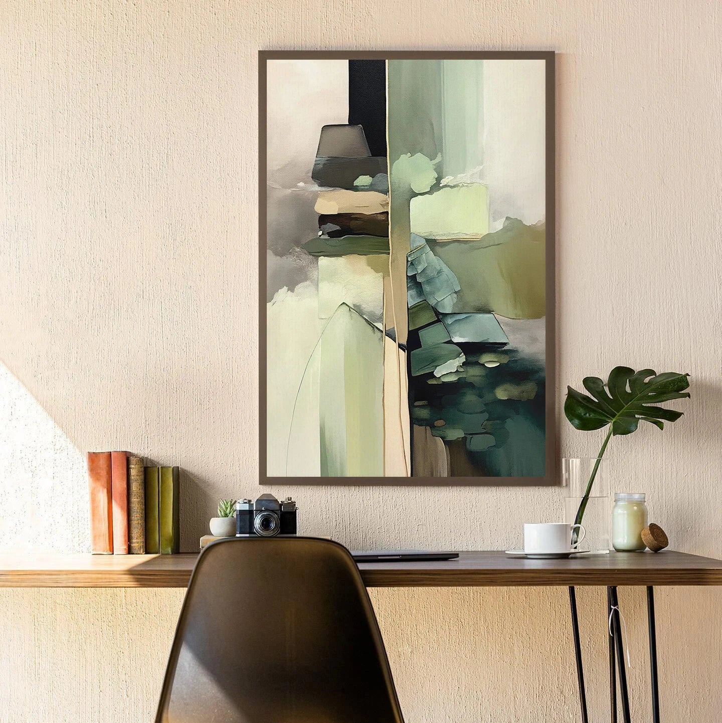 Abstract art print on a wall above a desk with books and decor items.