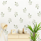 Wall with green leaf decals, wooden cabinet, lamp, and plant
