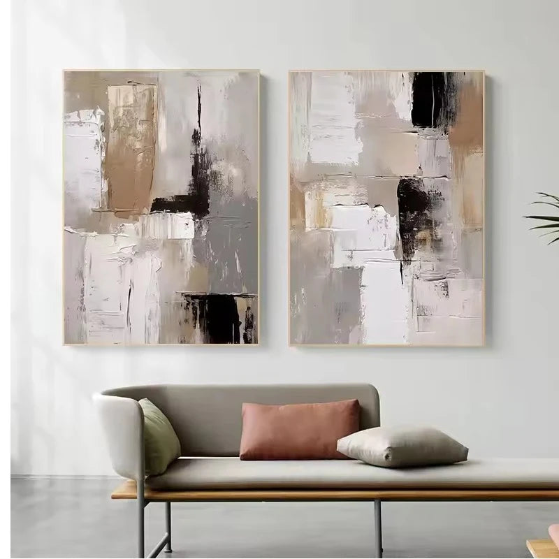 Two abstract paintings on a wall above a sofa with cushions.