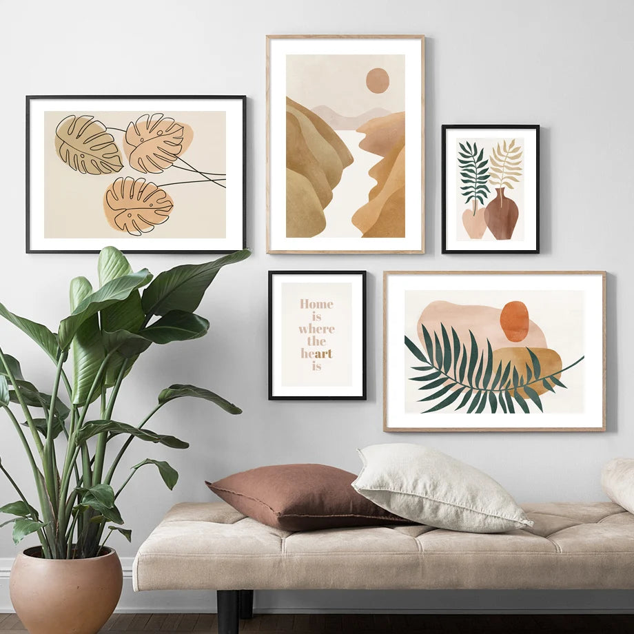 Framed abstract art prints on a wall above a sofa with decorative pillows and a plant.
