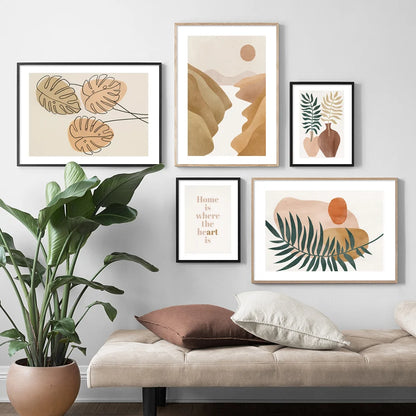 Framed abstract art prints on a wall above a sofa with decorative pillows and a plant.