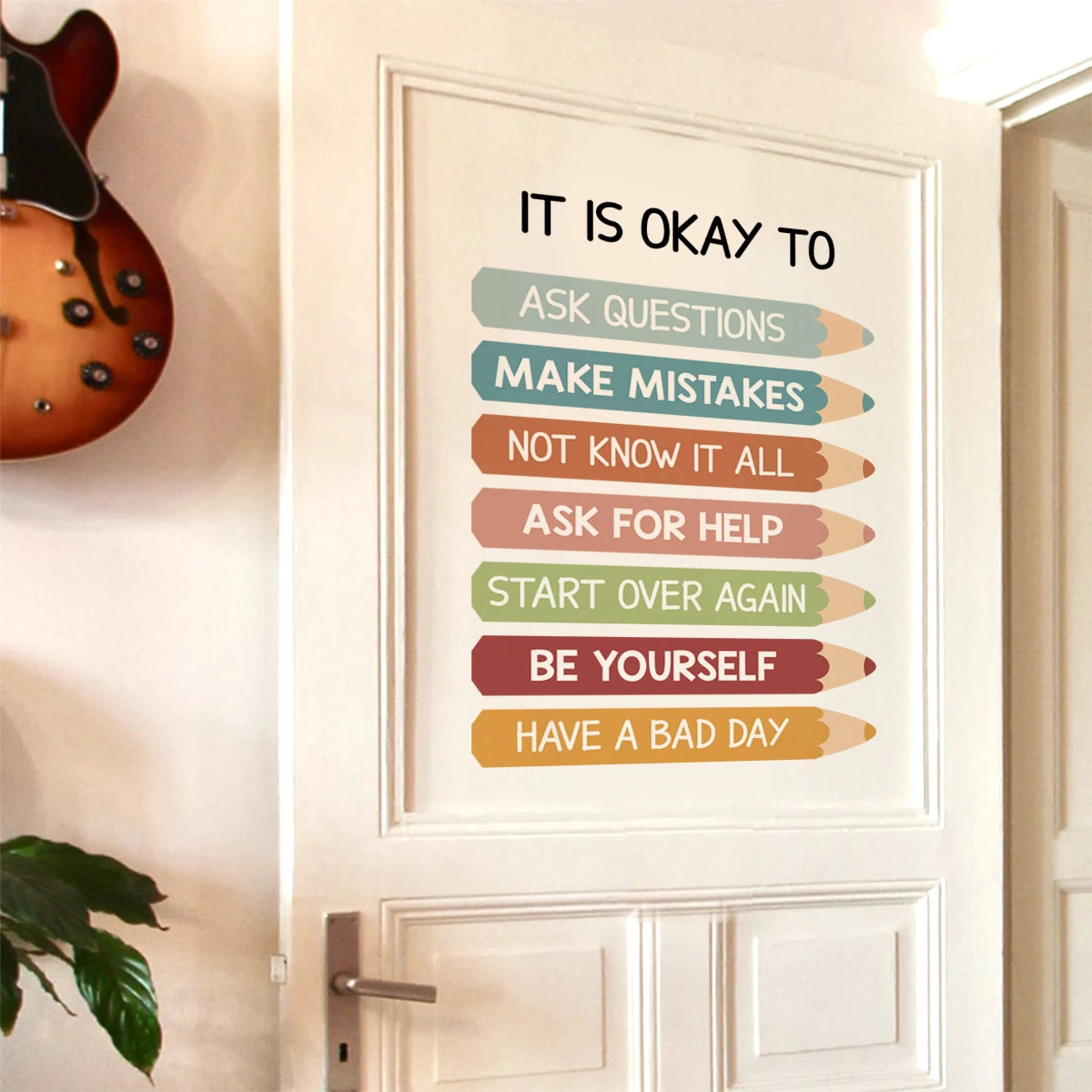 Motivational poster on a door with colorful text and a guitar in the background.