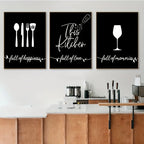 Three black framed prints with white text and icons on a wall above a kitchen counter.