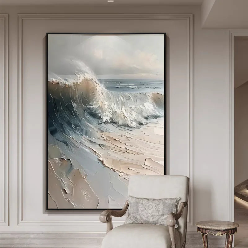 Framed artwork of a wave crashing onto a beach in a room with a chair and side table.