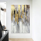 Abstract painting with gold and gray tones on a white wall.