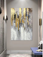 Abstract art painting with gold and gray tones on a wall in a modern interior setting.