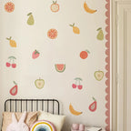 Wall with fruit-themed wall decals above a bed with decorative pillows.