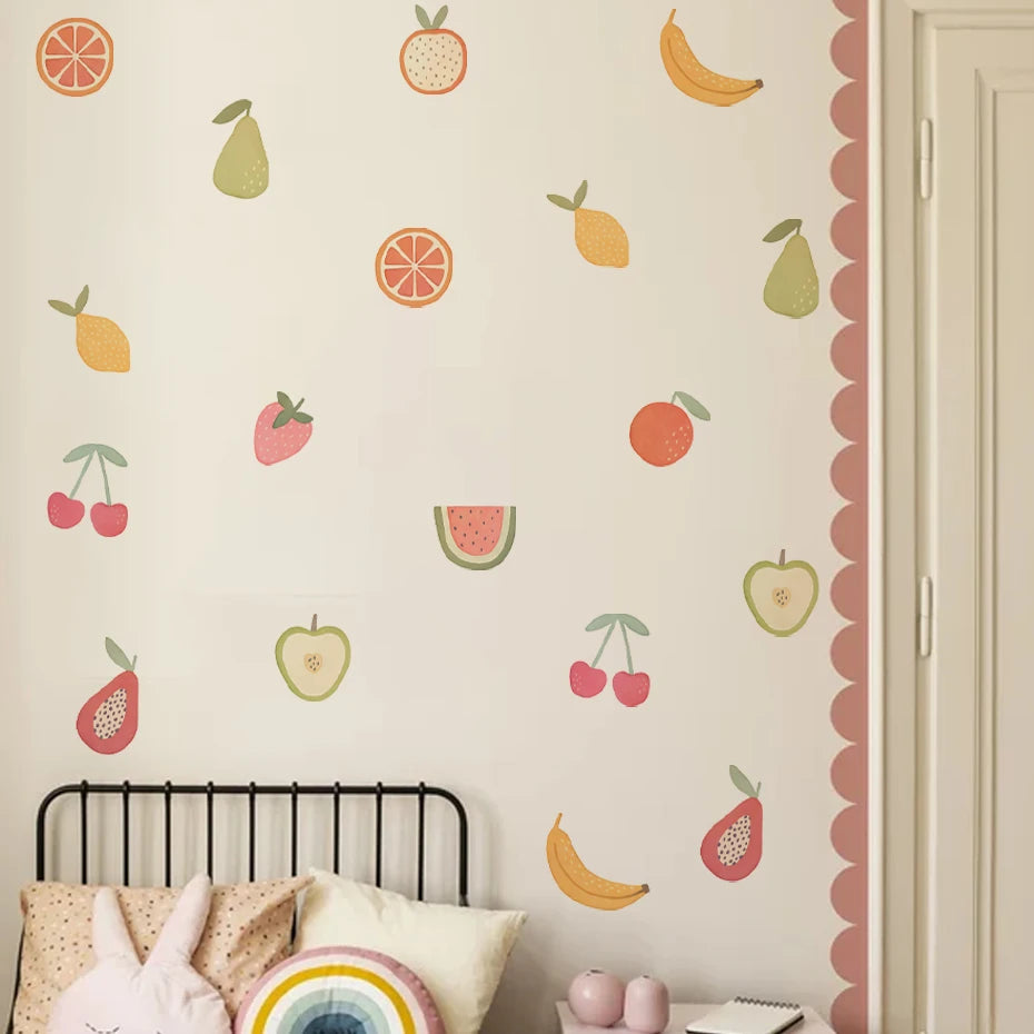 Wall with fruit-themed wall decals above a bed with decorative pillows.